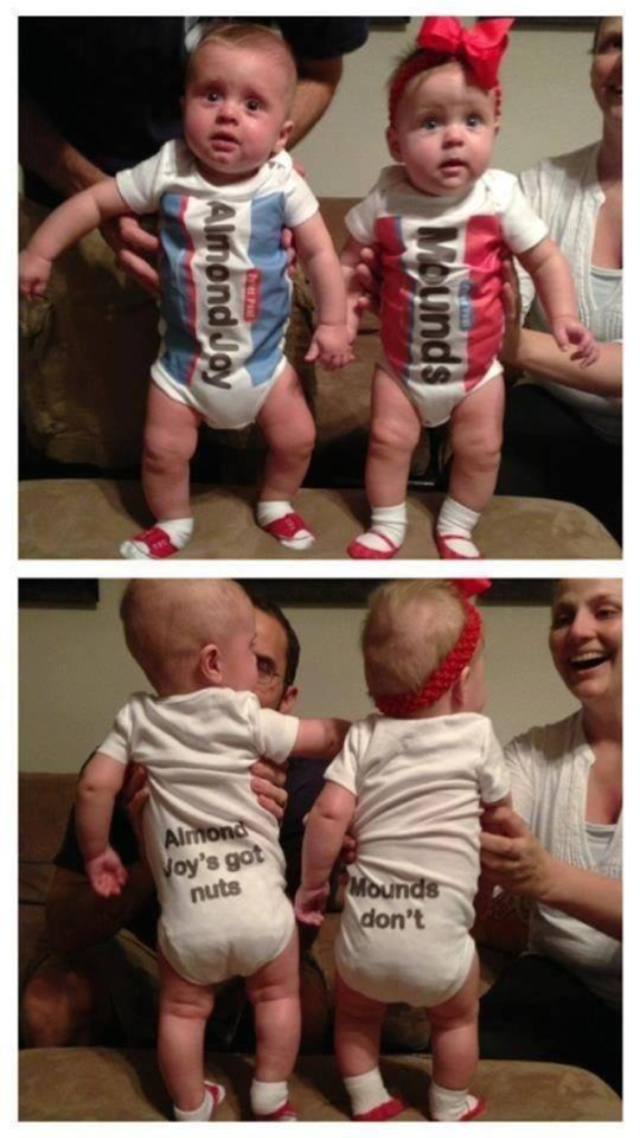 Twin babies wearing onesies. The boy's has the Almond Joy candy bar logo and the girl's has the Mounds label. The back of the boy's says "Almond Joy has nuts." The girl's says "Mounds don't."