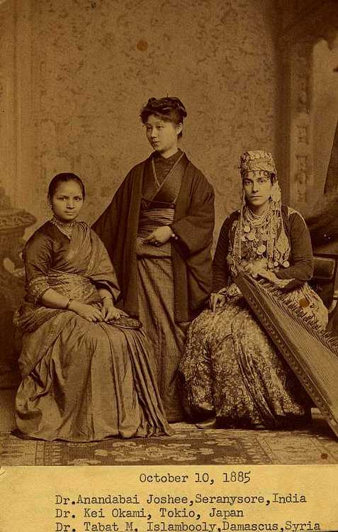 A sepia tone photo of three women - one from India, one from Japan, one from Syria - in period, traditional dress. Caption reads "October 10th, 1885:  Dr. Anandibai Joshee, Seranysore, India. Dr. Kei Okami, Tokio, Japan. Dr. Sabat Islambooly, Damascus, Syria." 