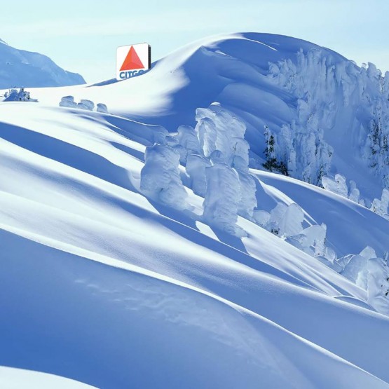 A large snow drift on a snow covered mountain with a photoshopped Citgo sign peeking out from it.