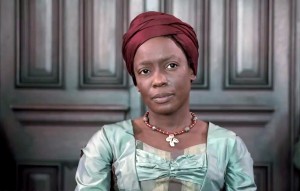 Aminata, a former slave, is shown in fashionable late colonial dress with her hair wrapped in burgundy linen.